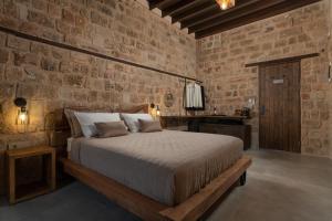a bedroom with a bed and a brick wall at Ancient Knights Luxury Suites in Rhodes Town