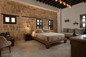 a bedroom with a bed and a stone wall at Ancient Knights Luxury Suites in Rhodes Town