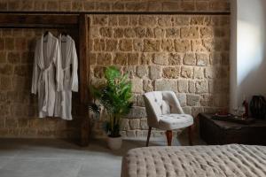 a bedroom with a bed and a chair and a brick wall at Ancient Knights Luxury Suites in Rhodes Town