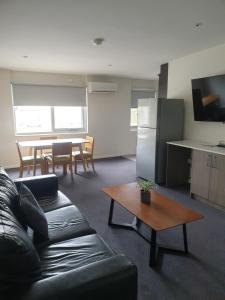 古尔本Carlton Suites的客厅里有一张黑色沙发和一张桌子