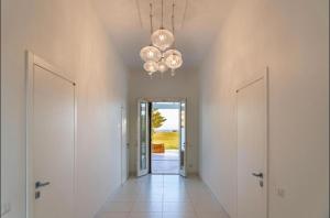 un couloir avec deux portes blanches et un lustre dans l'établissement Villa Caponegro, à Avola