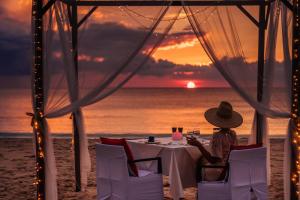 
a man sitting at a table in front of a sunset at Layana Resort & Spa - SHA Extra Plus in Ko Lanta
