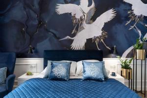 a bedroom with a blue bed with white birds on the wall at Sanhaus Apartments - Apartament Garda, 2 sypialnie, parking in Sopot