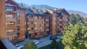 an apartment building with cars parked in a parking lot at Сладко студио в Пирин с голф и СПА комплекс in Razlog