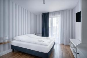 a white bedroom with a bed and a window at W Starym Porcie - Apartament - 2 sypialnie in Krynica Morska