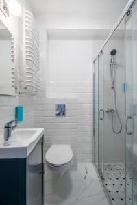a white bathroom with a toilet and a shower at W Starym Porcie - Apartament - 2 sypialnie in Krynica Morska