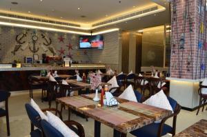 um restaurante com mesas e cadeiras e um bar em Orchid Hotel no Dubai