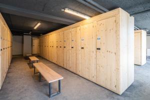 rząd drewnianych szafek w pokoju z ławkami w obiekcie Vacancéole - Les Ecrins d'Auris w mieście Auris