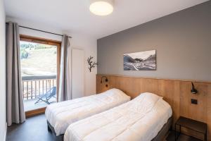 a bedroom with two beds and a balcony at Vacancéole - Les Ecrins d'Auris in Auris