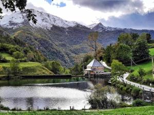 un lago con una casa y montañas en el fondo en Apartamentos Rurales La Laguna Somiedo, en Valle de Lago