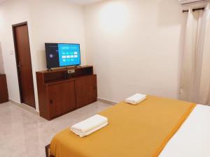 a bedroom with a bed and a tv on a table at Chippy Residency in Chennai