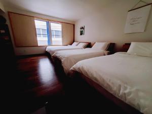 a row of three beds in a room with a window at Rooms in Tokyo