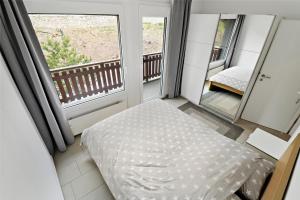 クランにあるAppartement en plein centre de Crans Montanaのベッドとバルコニーのある寝室