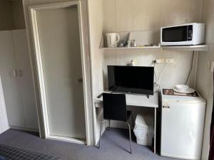 a room with a desk with a computer and a microwave at Junction Hotel Moora in Moora
