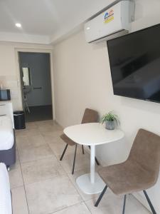 古尔本Carlton Suites的有一张桌子、两把椅子和一台电视的房间