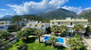 an aerial view of a house with palm trees and mountains at Manolis Apartments plakias in Plakias