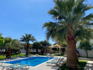 una piscina con palmeras y tumbonas en Manolis Apartments plakias en Plakias