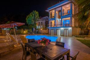 a house with a table and a swimming pool at night at Infinity Olympia Villas in Oludeniz