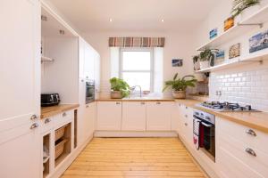 a kitchen with white cabinets and a wooden floor at JOIVY Gorgeous 1-bed flat with a shared garden in Edinburgh