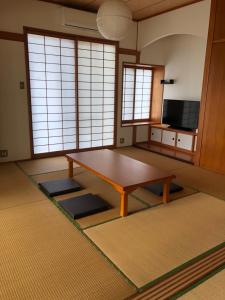 un soggiorno con tavolo in una camera con finestre di やんばる別荘三原でーじまぎー -Yanbaru stay MIHARA VILLA GRANDE- a Nago