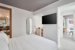 a hotel room with a bed and a television at Adorno Beach Hotel and Suites in Ornos