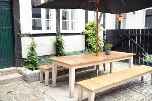 a wooden table with an umbrella and two benches at Magni Boutique Hotel in Braunschweig