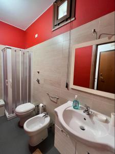 een badkamer met een toilet, een wastafel en een spiegel bij La Colombaia in Trapani