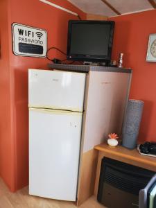 Un refrigerador en una habitación con una computadora encima. en Mobil home chez l habitants, en Saint-Jean-de-Monts