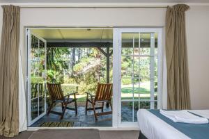 a bedroom with a bed and two chairs on a porch at Northridge Golf Resort in Orewa