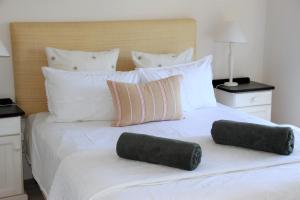 Una cama blanca con dos almohadas encima. en L4 Goose Valley Golf Estate, en Plettenberg Bay