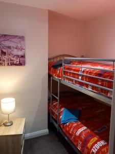 2 Etagenbetten in einem Zimmer mit einem Schreibtisch und einer Lampe in der Unterkunft clazzers apartment 2 in Bridlington