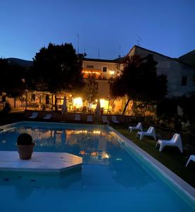 a swimming pool at night with chairs and a building at Hotel Borgo Antico in Fabriano