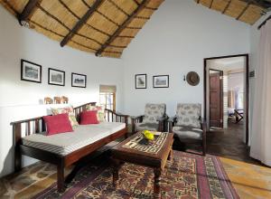 a living room with a couch and a table and chairs at Onguma Forest Camp in Namutoni