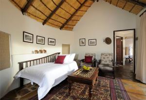 a bedroom with a bed and a table and a chair at Onguma Forest Camp in Namutoni