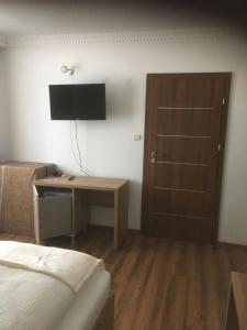 a bedroom with a bed and a desk with a television at Vila Maria băile felix in Baile Felix