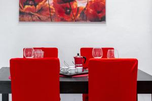 a dining room table with red chairs and a painting at Piazza delle Vettovaglie Historic Center Eco Flat in Pisa