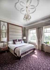 Woodlands Park Hotel في كوبهام: غرفة نوم بسرير كبير وثريا