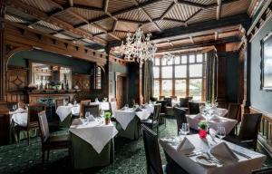 a restaurant with white tables and chairs and a chandelier at Woodlands Park Hotel in Cobham