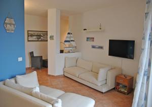 sala de estar con 2 sofás blancos y TV de pantalla plana en Gallura 2 en La Maddalena