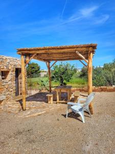 een houten paviljoen met een witte stoel en een tafel bij Gallipoli lato sud, TRULLO ANTICA DIMORA in Torre Suda