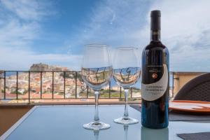una bottiglia di vino e due bicchieri di vino su un tavolo di CASTELSARDO- Elegante Appartamento vista Mare a Castelsardo