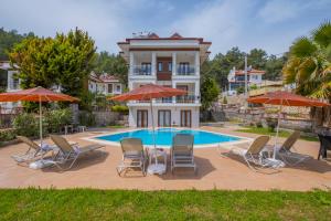 a villa with a swimming pool with chairs and umbrellas at Infinity Olympia Villas in Oludeniz