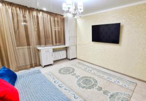 ein Wohnzimmer mit einem TV an der Wand in der Unterkunft Абсолютно новая квартира класса ЛЮКС in Taras