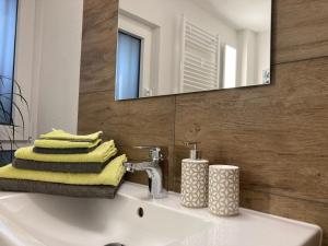 een badkamer met een wastafel, een spiegel en handdoeken bij Fewo Vulkaneifel in Tettscheid