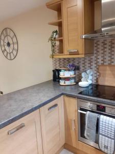 a kitchen with wooden cabinets and a clock on the wall at Alexandra place Skipton child and dog friendly in Skipton