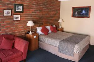 - une chambre avec un lit, une chaise et un mur en briques dans l'établissement Bendigo Haymarket Motor Inn, à Bendigo