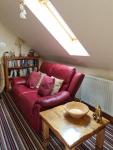 a red couch in a living room with a table at Lyde Cross Coach House in Hereford