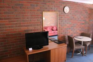 a room with a desk with a tv and a brick wall at Bendigo Haymarket Motor Inn in Bendigo
