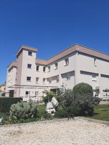 un grand bâtiment blanc avec des buissons devant lui dans l'établissement Villa Gaga, à Međugorje