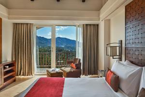 a hotel room with a large bed and a large window at Fariyas Resort Lonavala in Lonavala